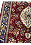 Close-up of burgundy field showing intricate floral motifs in wool and silk