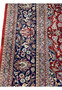 Side border close-up showing floral motifs on navy Kashan rug border