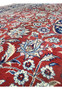 Close-up of red field on antique Persian Kashan rug showing layered floral vines and precise hand-knotted wool texture
