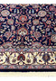 Lower border close-up of a Persian Sarough kork rug with ivory ground, floral rosettes, scrolling vines, and navy framing line