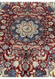 Center medallion closeup of Persian Tabriz rug with ivory rosette, navy outline, and burgundy floral field