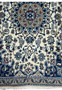 Lower border detail of Persian Nain rug with blue and beige floral patterns