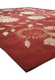 Angled perspective of a modern Tibetan wool and silk rug showing the rich red background, botanical floral design, and subtle silk sheen across the surface