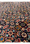 Close view of dense herati style geometric motifs on a deep red field in a Persian Bijar iron rug