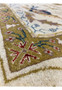 Close-up of floral pattern showing ivory, olive, blue, and gold tones in a Jaipur wool rug