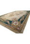 Angled perspective of a large French Aubusson rug showing emerald green border, floral garlands, beige field, and refined European symmetry