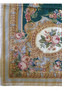 Closeup of emerald green border on French Aubusson rug with rose garlands, classical cartouches, muted gold accents, and pastel detailing
