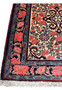 Detailed border view of a 3'4 x 4'8 Persian Bijar rug with rose flower garlands, navy ground, intricate vine work, and traditional hand knotted structure