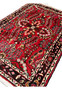 Angled perspective of a Persian Darjazin rug emphasizing pile height, dense knotting, vivid crimson tones, and dimensional floral motifs across the surface