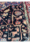 Close-up of pictorial tribal motifs in an antique Nahavand rug featuring animals, symbolic forms, and saturated indigo wool field