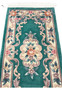 Detailed midfield image of emerald green Aubusson rug emphasizing sculpted floral vines and dimensional Art Deco decorative elements