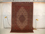 Hanging view of a 6'5 x 10 authentic Persian Bijar rug showing its firm iron rug structure, dense wool pile, crisp medallion design, and rich red color tones