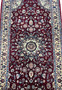 Close view of the central medallion on a Persian Tabriz rug showing ivory and navy detailing, fine knotting, and dense floral symmetry on a burgundy field.