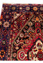 Upper border detail of a Persian Gholtogh rug featuring navy ground, repeating tribal motifs, geometric blossoms, and strong color contrast