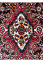 Close-up of the medallion in a Persian Gholtogh rug revealing precise knotting, rich red tones, navy outlines, and tribal geometry