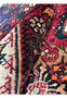 Rolled view of a Persian Gholtogh rug highlighting thick wool pile, saturated red and navy colors, sturdy tribal weave, and flexible hand-knotted structure