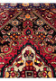 Upper field detail of a 3'4 x 5'5 Persian Gholtogh rug showing dense tribal motifs, deep red ground, navy accents, and crisp geometric symmetry