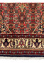 Lower border view of a Persian Bijar rug featuring layered framing, deep red tones, floral rosettes, and strong visual definition