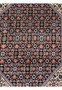 Central design closeup of a Persian Bijar iron rug showing layered geometric shapes, ivory detailing, red field, navy background, and precise wool craftsmanship
