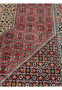 Geometric pattern closeup on a Persian Bijar rug with compact floral diamonds, dark navy field, red highlights, ivory motifs, and exceptionally dense weaving