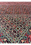 Inner border closeup of a Persian Bijar rug highlighting repeating geometric motifs, ivory background, red accents, and precise high-density wool weaving