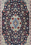 Central field of Persian Isfahan rug featuring ivory medallion, light blue arabesques, burgundy floral accents, and dense fine knot structure