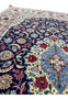 Field closeup of super fine Isfahan rug showing navy wool ground, silk floral motifs, and exceptionally tight knot structure