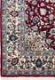 Border close up of Persian Tabriz rug displaying floral rosettes, light blue framing, ivory background, and crisp hand knotted detail