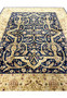 Midfield detail of a distressed Oriental Agra rug highlighting scrolling floral vines, faded navy background, softened gold accents, and natural color wear