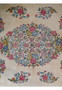 Close-up of the central medallion on a Persian Kerman rug showing layered floral clusters in pink, light blue, soft green, and pale yellow tones