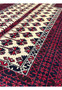 Angled perspective of a Persian Baluch prayer rug emphasizing wool pile texture, bold contrast, and geometric tribal design
