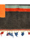 Persian Gabbeh tribal rug detail showing dark charcoal wool field with orange stripe and sage green band plus red and blue hand tied tassels