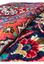 Rolled edge view of Persian Mahal rug revealing thick wool pile, sturdy foundation, and vibrant red and blue border colors