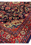 Close view of Persian Mahal rug inner border featuring red floral guard stripes, small blossoms, and navy outlines framing the deep blue field