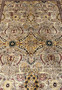 Closeup of central medallion area with golden motifs, rust florals, and fine hand knotted detail.