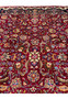 Close view of Mashad rug field showing dense floral arabesques, vibrant red background, and fine wool knotting