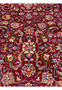 Pattern detail of Persian Mashad rug highlighting repeating floral medallions, vine scrolls, and balanced symmetry across the red field.