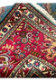 Folded corner of 10x13 Persian Tabriz rug showing crimson border against sky blue field