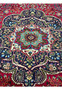 Medallion closeup of 10x13 Persian Tabriz rug, eight-petal floral rosette with teal and crimson