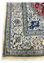 Close view of ivory border on red Persian Nain rug with scrolling floral motifs and fine symmetrical drawing