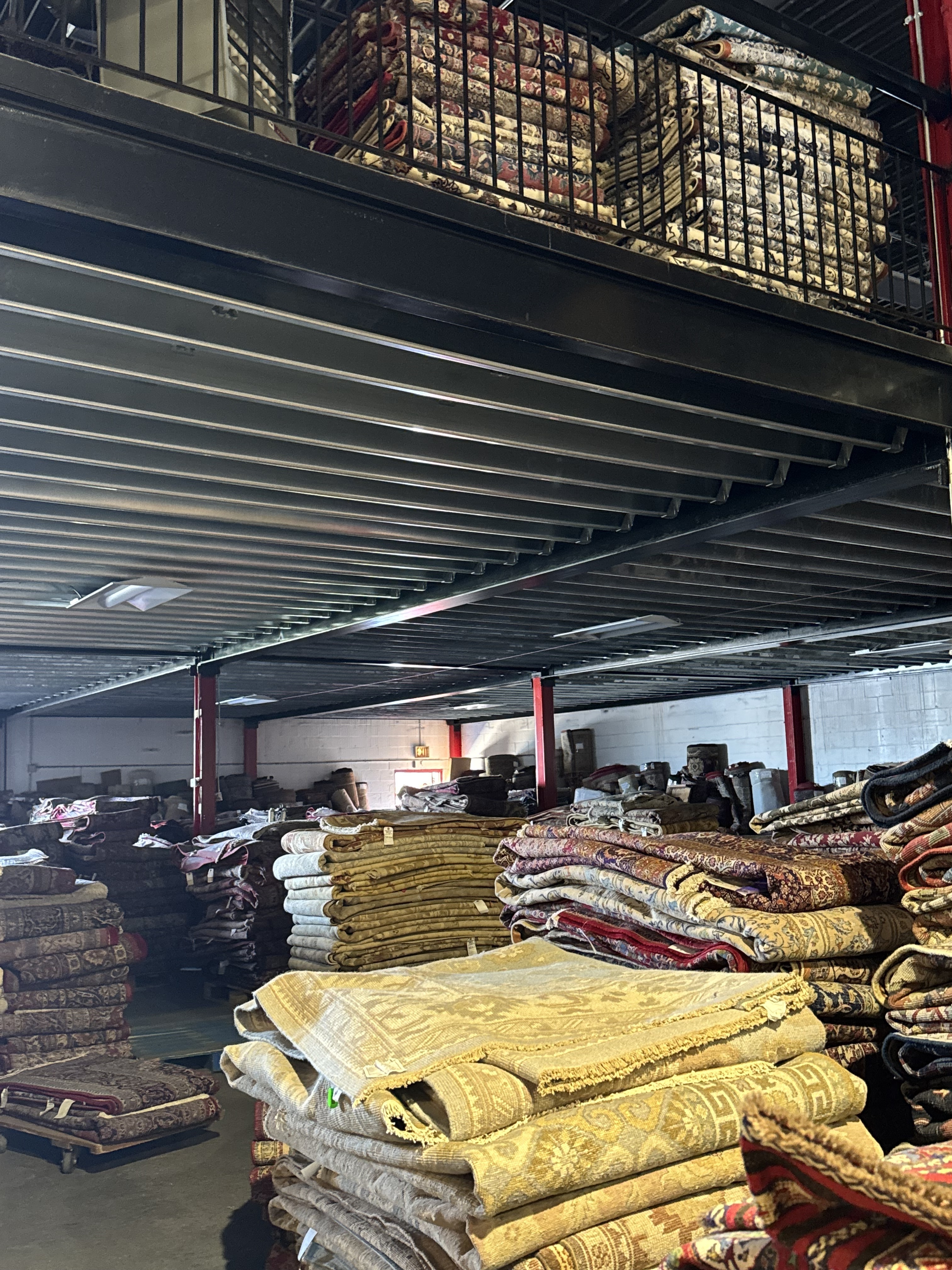 Rolled handmade rugs of every size lined up on the Rugs.net warehouse floor