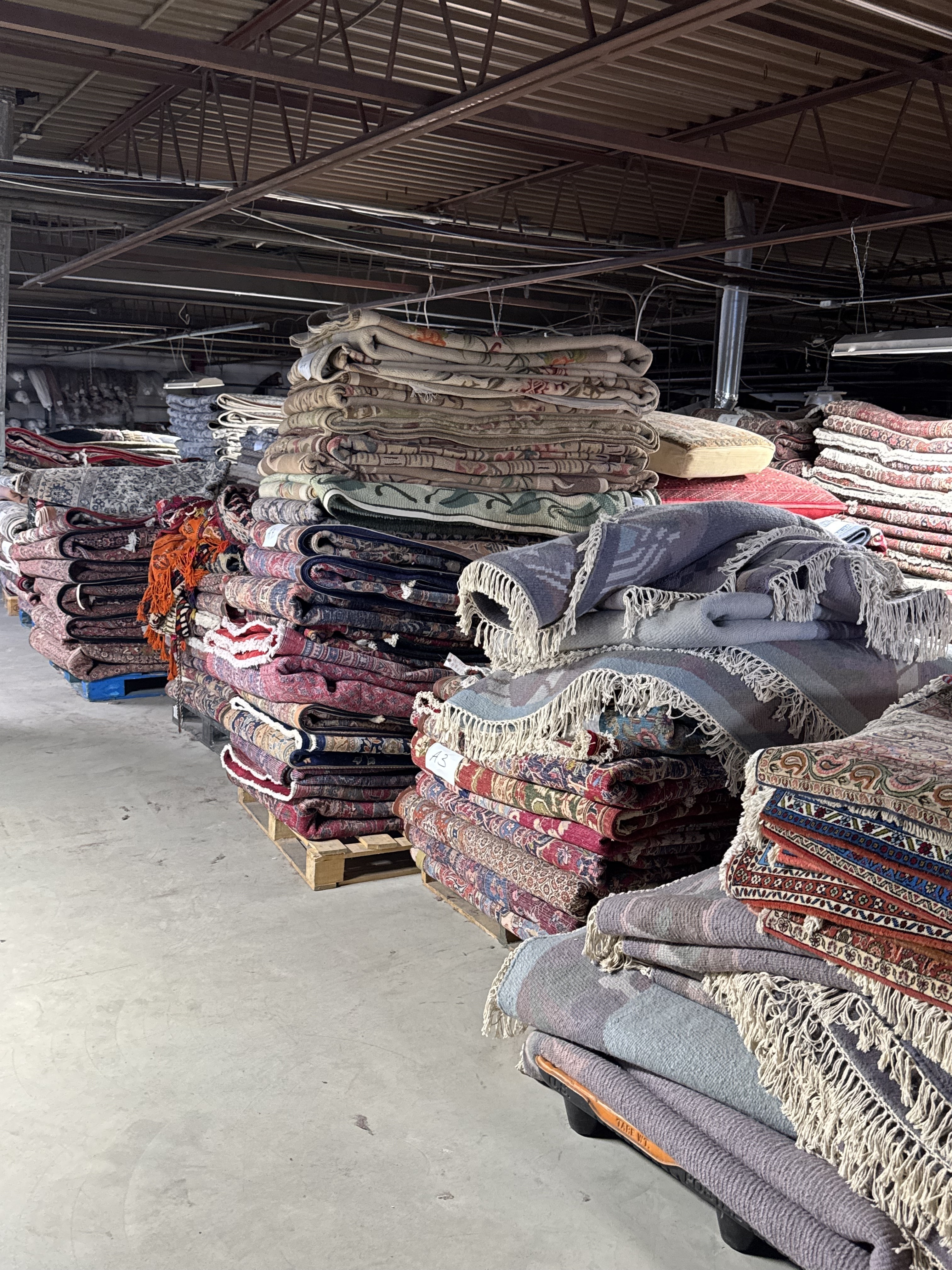 Rows of rolled Oriental and Persian rugs in every size waiting on the warehouse racks