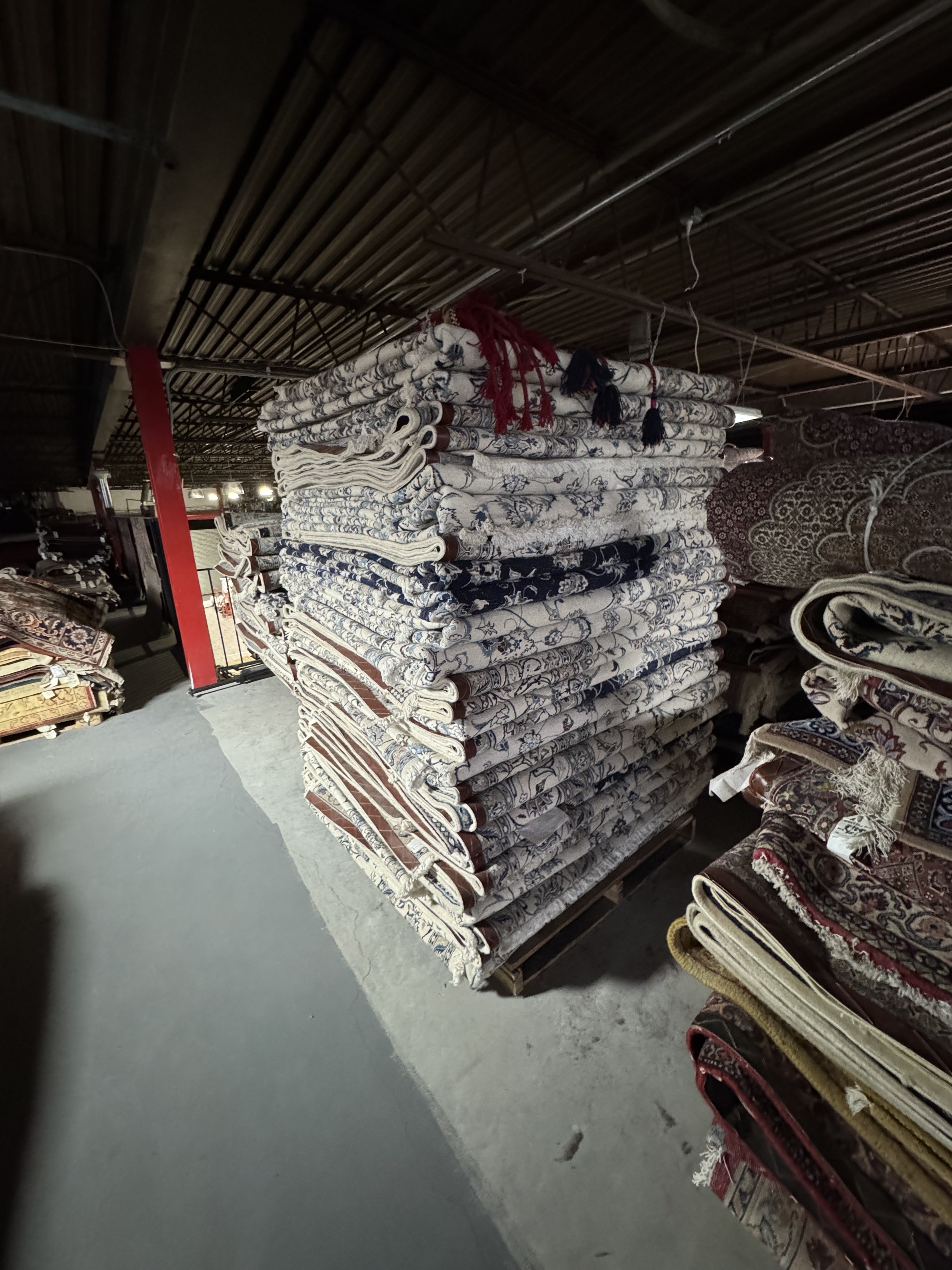 Hand-knotted Persian rugs stacked on pallets in the Rugs.net Freeport New York warehouse