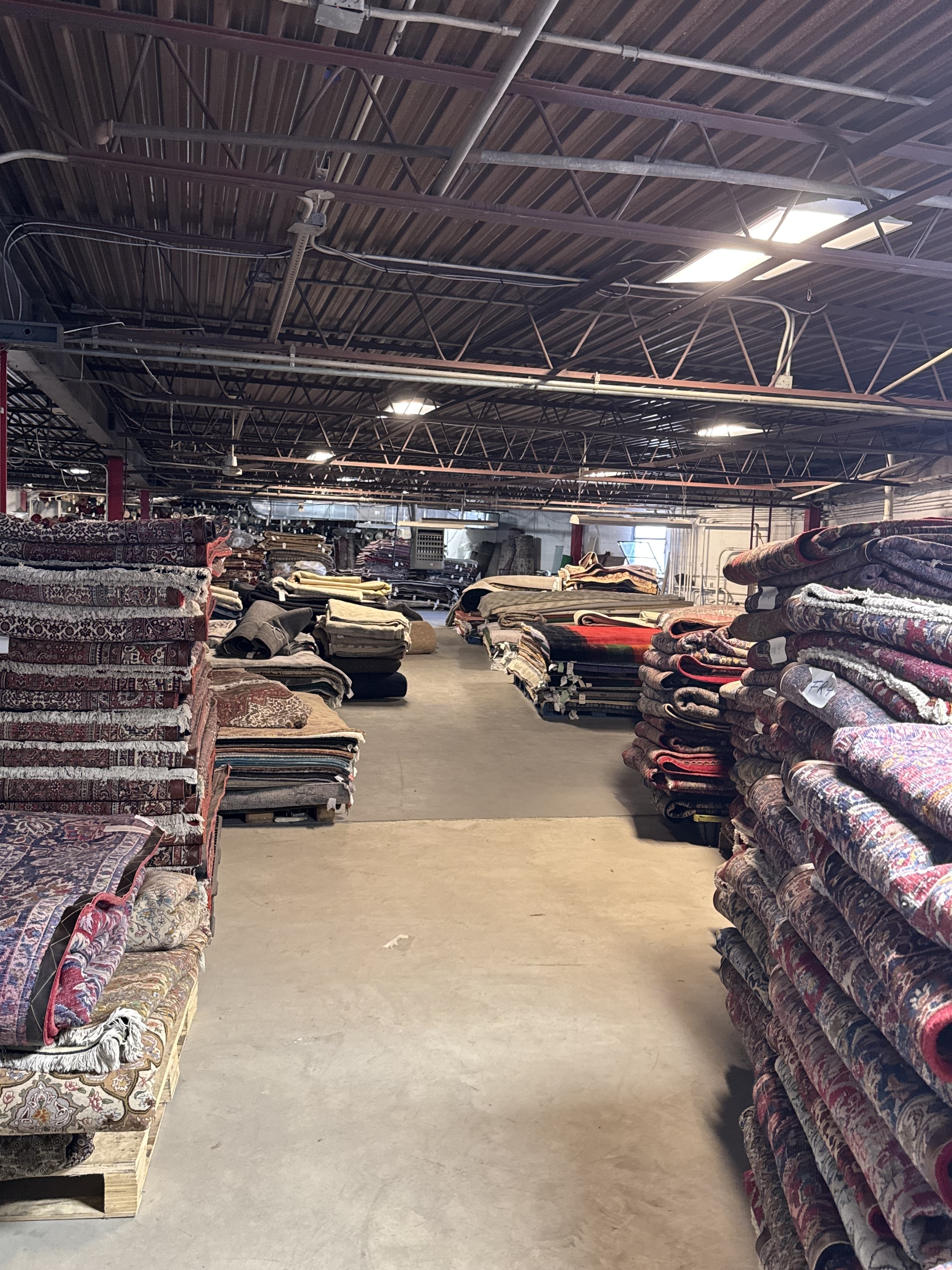 Upstairs storage level of the Rugs.net warehouse stacked with rugs being catalogued for the site