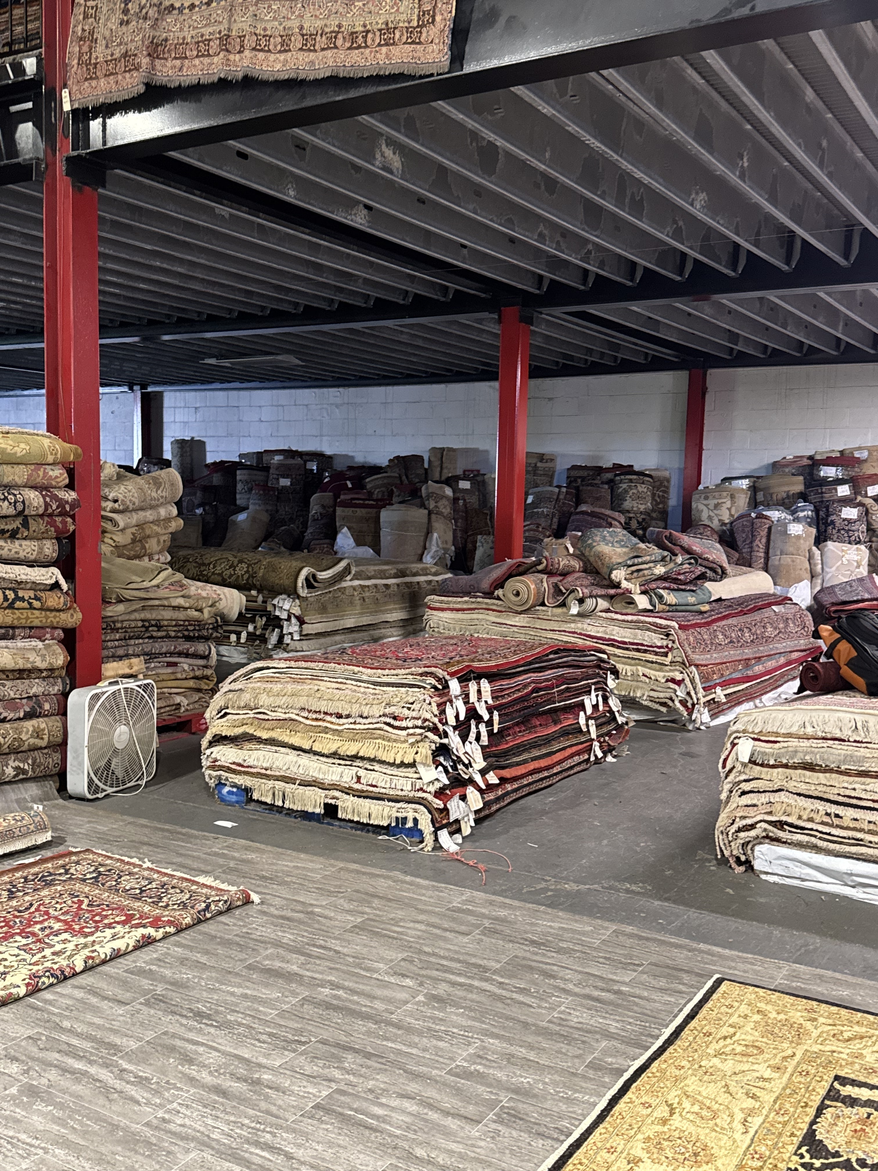 Handmade rugs unrolled for inspection and photography inside the Rugs.net warehouse