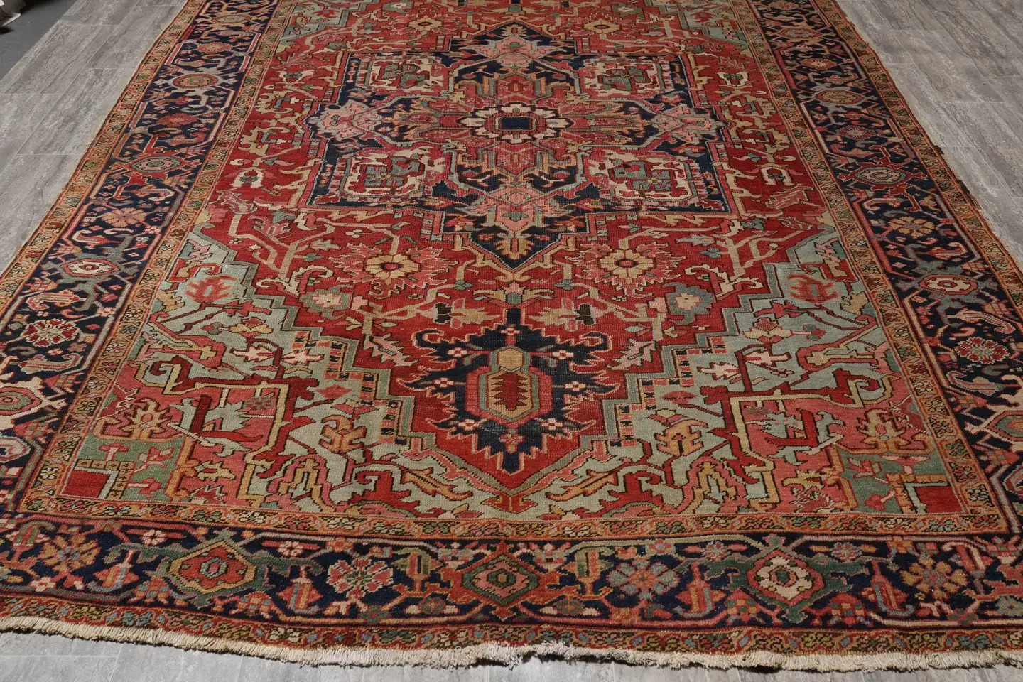 An antique Persian rug with a low, softened pile and faded colours after a century of use