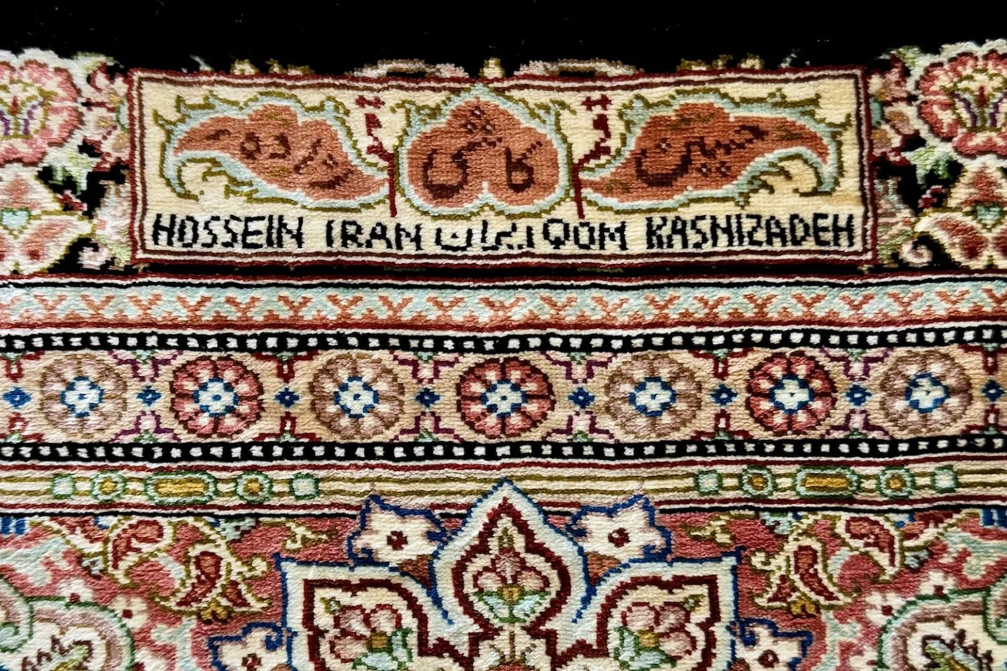 A signature cartouche reading Hossein Kashizadeh, Qom, woven in Persian script into the border of a pure silk rug