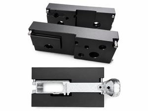 An industrial-style product hero shot featuring the modular aluminum machining jig assembled and clamped securely in a heavy-duty bench vise, positioned against a clean workshop background.