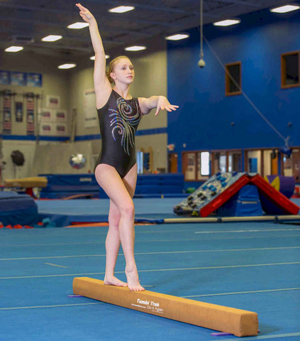 Gymnast (13-15) striking pose on balance beam Stock Photo - Alamy