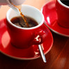 Hot coffee being poured into a red espresso cup on matching saucer